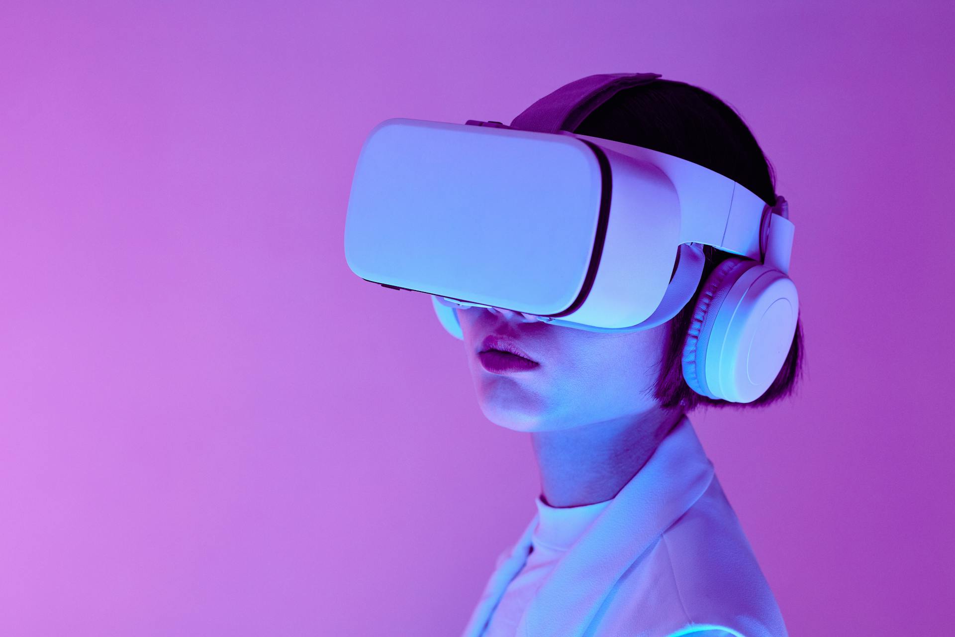 A TrendSnip user immersed in a virtual reality experience, wearing a VR headset and over-ear headphones, against a striking purple backdrop. Their light-colored outfit is bathed in soft, colorful lighting, evoking a futuristic and captivating ambiance.